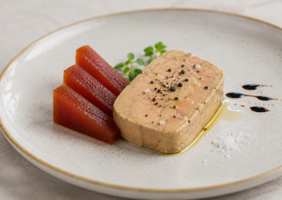 Slice of membrillo with orange served on a plate with browned pork or pate, carrots and black pepper garnish